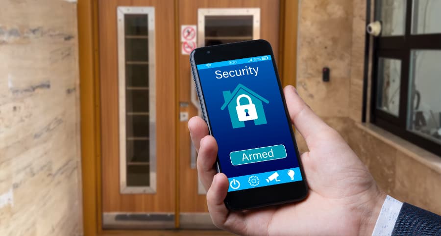 Person using mobile device to arm a home security system